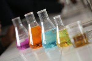 Chemistry beakers containing different coloured liquids sat on a chemistry bench.