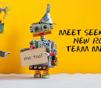 A image of a yellow background with two robots greeting each other and text to the right of them reading "Meet Seek Social's new robots team members"