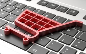 A pink plastic shopping cart laying atop a laptop keyboard.