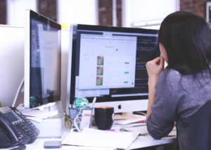 A web designer or SEO expert examining a site on a dual-monitor setup