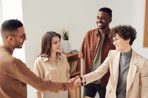 two people smiling and shaking hands, as two more people look on, smiling