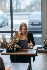A woman in a modern office setting, sat at adesk and working on a laptop. The room she's in is decorated for Christmas.